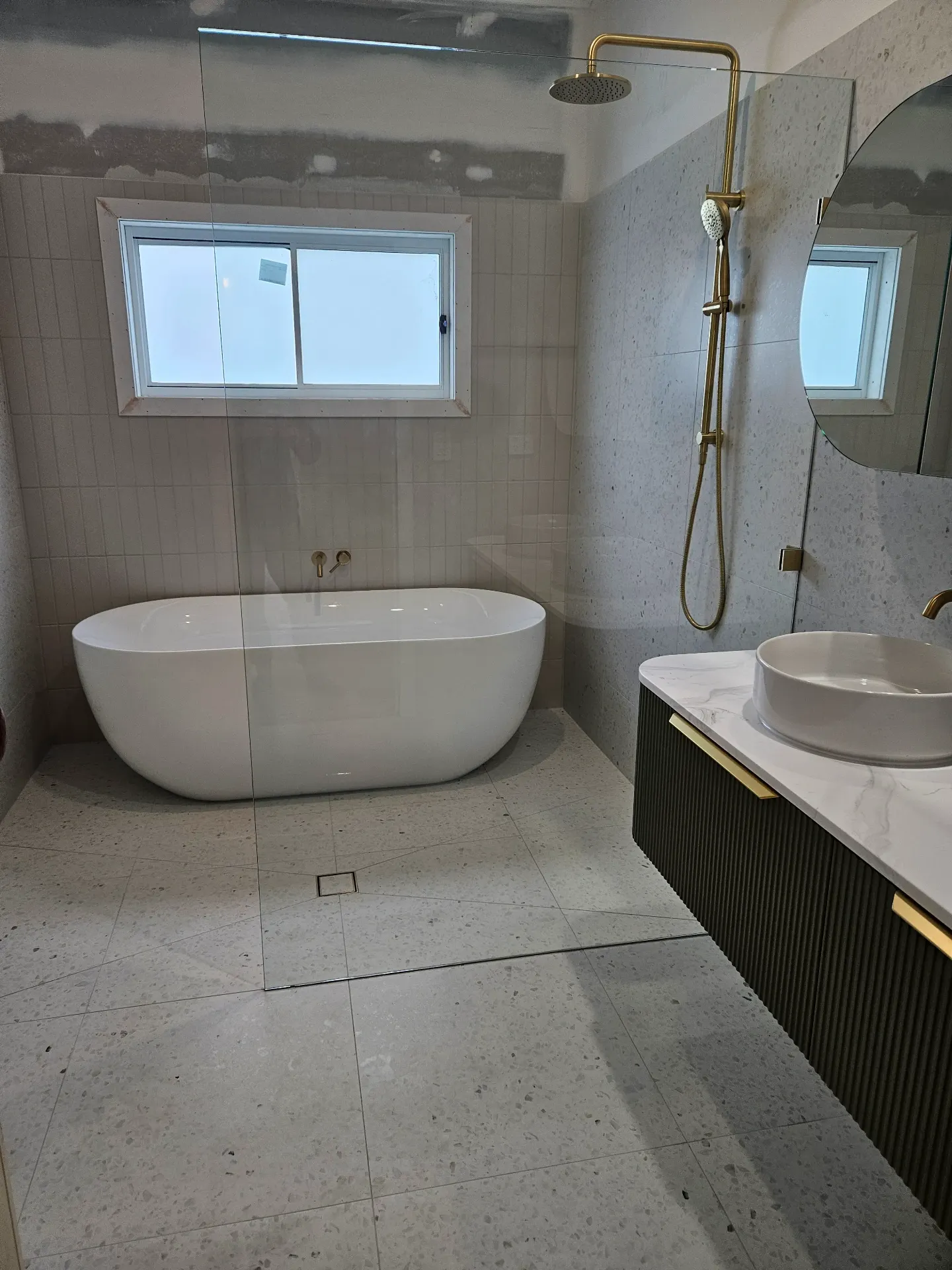 Terrazzo bathroom with freestanding tub and brass fixtures