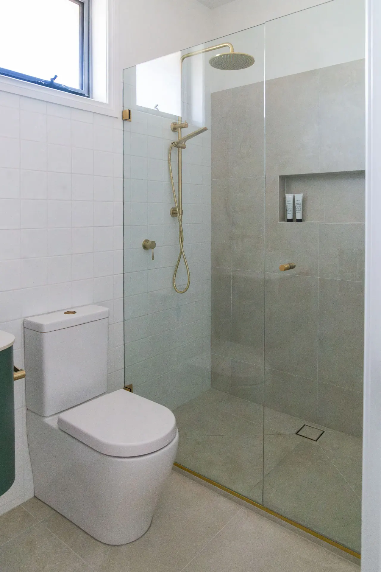 Editorial walk-in shower with grey tile and brass fixtures