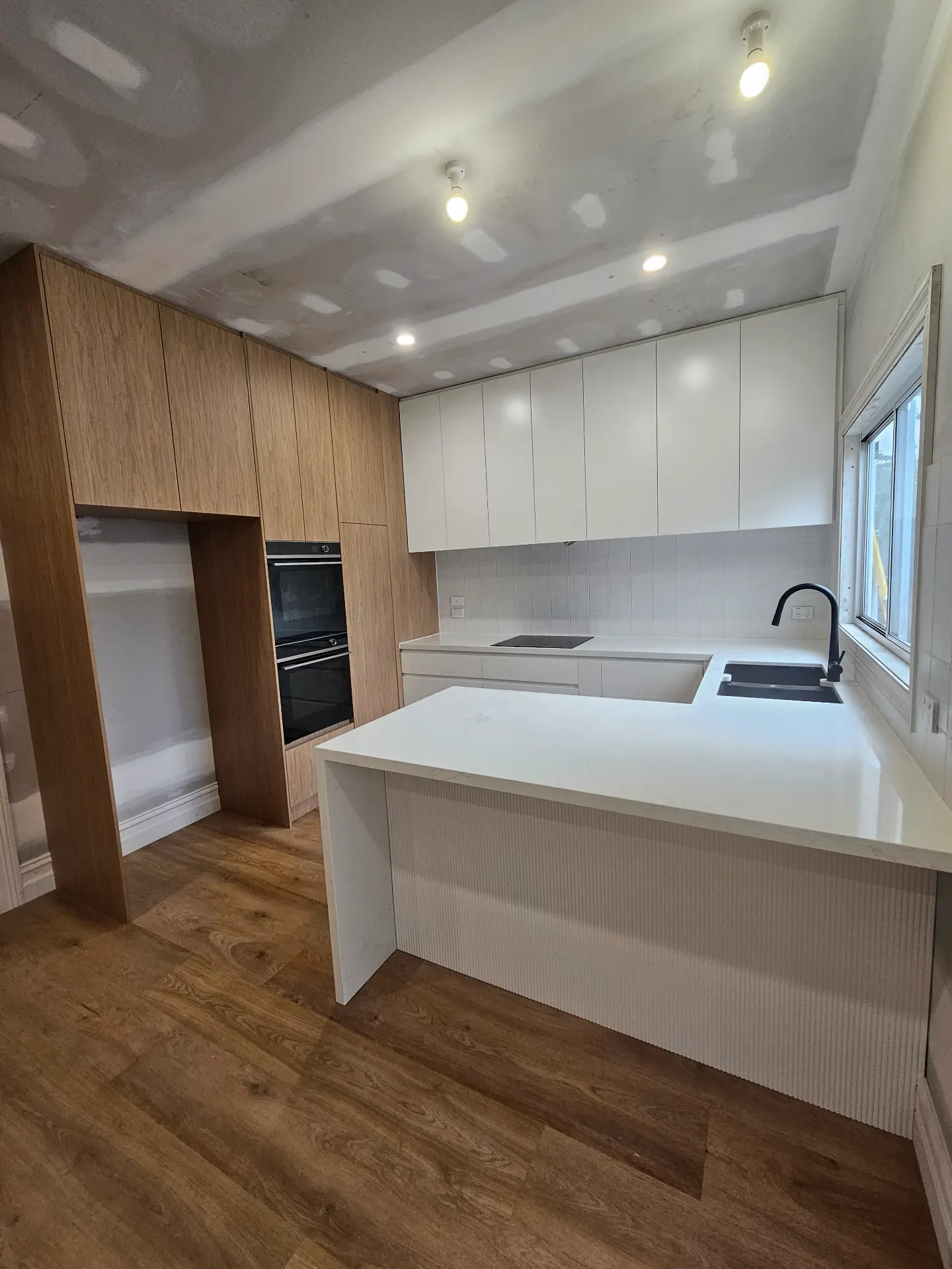 White kitchen with fluted timber island and stone benchtop